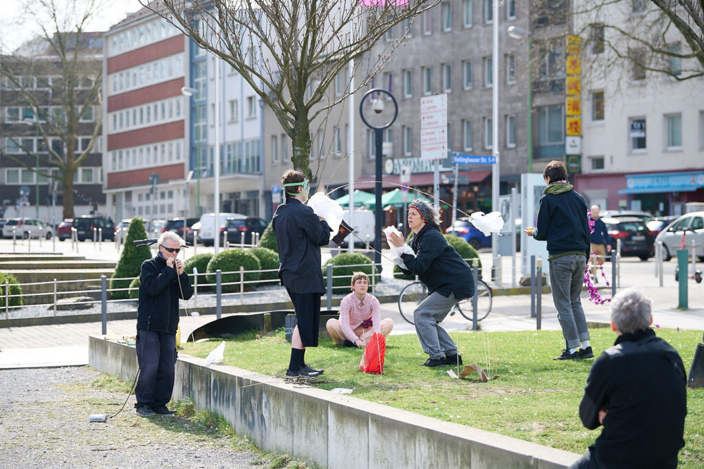 A group of people, including a child and adults, are enjoying a sunny day in a park, engaging in activities and conversations.
