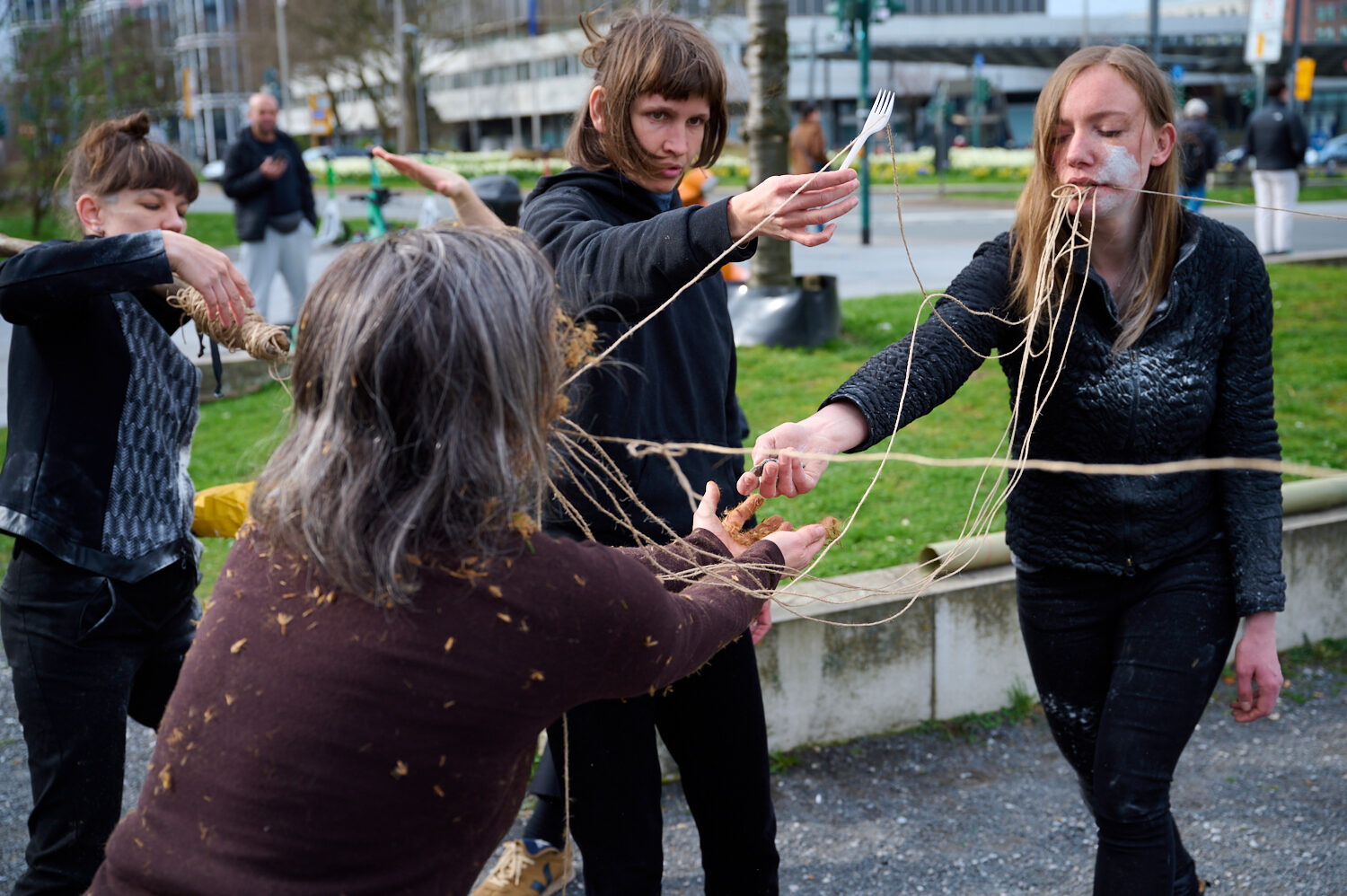 Five individuals interact in an outdoor setting, connecting with strings, creating an artistic performance.